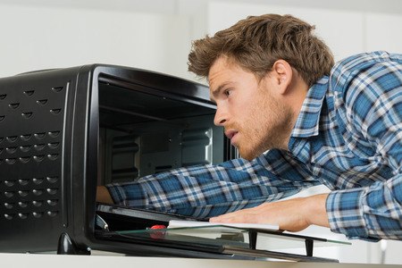 repairman fixing oven in kitchen